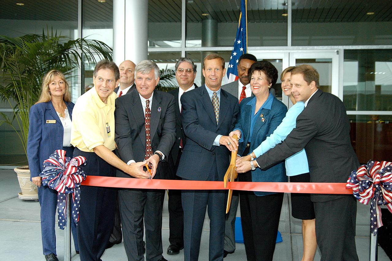 Representatives of the NASA-Kennedy Space Center and the state of Florida prepare to cut the ribbon officially opening the Space Life Sciences Lab at a ceremony at the new lab. In the front row, from left, are Dr. Samuel Durrance, executive director of the Florida Space Research Institute; Jim Kennedy, director of the Kennedy Space Center; Frank T. Brogan, president of the Florida Atlantic University; The Honorable Toni Jennings, lieutenant governor of the state of Florida; and Catherine and Grier Kirkpatrick, children of the late Sen. George Kirkpatrick. In the back row, from left, are Debra Holliday, director for Facilities and Construction, Florida Space Authority; Dan LeBlanc, president and chief operating officer of Delaware North Companies Parks and Resorts at KSC, Inc.; Jose Perez-Morales, NASA Project Manager for the Space Life Sciences Lab; and Capt. Winston E. Scott, executive director of the Florida Space Authority. Completed in August, the facility encompasses more than 100,000 square feet and was formerly known as the Space Experiment Research and Processing Laboratory or SERPL. The state, through the Florida Space Authority, built the research lab which is host to NASA, NASA’s Life Sciences Services contractor Dynamac Corp., Bionetics Corp., and researchers from the University of Florida. Dynamac Corp. leases the facility. The Florida Space Research Institute is responsible for gaining additional tenants from outside the NASA community.