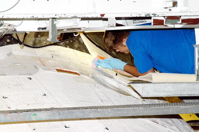 NASA image: KENNEDY SPACE CENTER, FLA. - In the Orbiter Processing Facility, United Space Alliance technician Jamie Haynes does a gap test on the tiles of the nose of orbiter Atlantis as part of return-to-flight activities.  Atlantis is scheduled for mission STS-114, a return-to-flight test mission to the International Space Station.