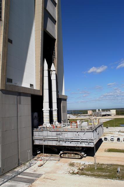 NASA image: KENNEDY SPACE CENTER, FLA. -  Mobile Launcher Platform (MLP) number 3 and a set of twin solid rocket boosters, atop the crawler-transporter, crawl out of the Vehicle Assembly Building (VAB) in support of the second engineering analysis vibration test on the crawler and MLP. In the background is another MLP.  The crawler is moving at various speeds up to 1 mph in an effort to achieve vibration data gathering goals as it leaves the VAB, travels toward Launch Pad 39A and then returns.  The boosters are braced at the top for stability.  The primary purpose of these rollout tests is to gather data to develop future maintenance requirements on the transport equipment and the flight hardware. Various parts of the MLP and crawler transporter have been instrumented with vibration data collection equipment.