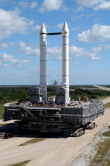 NASA image: KENNEDY SPACE CENTER, FLA. -  Mobile Launcher Platform (MLP) number 3 and a set of twin solid rocket boosters, atop the crawler-transporter, inch along the crawlerway in support of the second engineering analysis vibration test on the crawler and MLP. The crawler is moving at various speeds up to 1 mph in an effort to achieve vibration data gathering goals as it leaves the VAB, travels toward Launch Pad 39A (framed between the boosters), and then returns.  The boosters are braced at the top for stability.  The primary purpose of these rollout tests is to gather data to develop future maintenance requirements on the transport equipment and the flight hardware. Various parts of the MLP and crawler transporter have been instrumented with vibration data collection equipment.