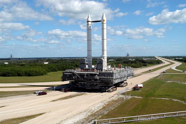 NASA image: KENNEDY SPACE CENTER, FLA. -  Mobile Launcher Platform (MLP) number 3 and a set of twin solid rocket boosters, atop the crawler-transporter, inch along the crawlerway in support of the second engineering analysis vibration test on the crawler and MLP. The crawler is moving at various speeds up to 1 mph in an effort to achieve vibration data gathering goals as it leaves the VAB, travels toward Launch Pad 39A (on the horizon at right; Pad 39B is at far left), and then returns.  The boosters are braced at the top for stability.  The primary purpose of these rollout tests is to gather data to develop future maintenance requirements on the transport equipment and the flight hardware. Various parts of the MLP and crawler transporter have been instrumented with vibration data collection equipment.
