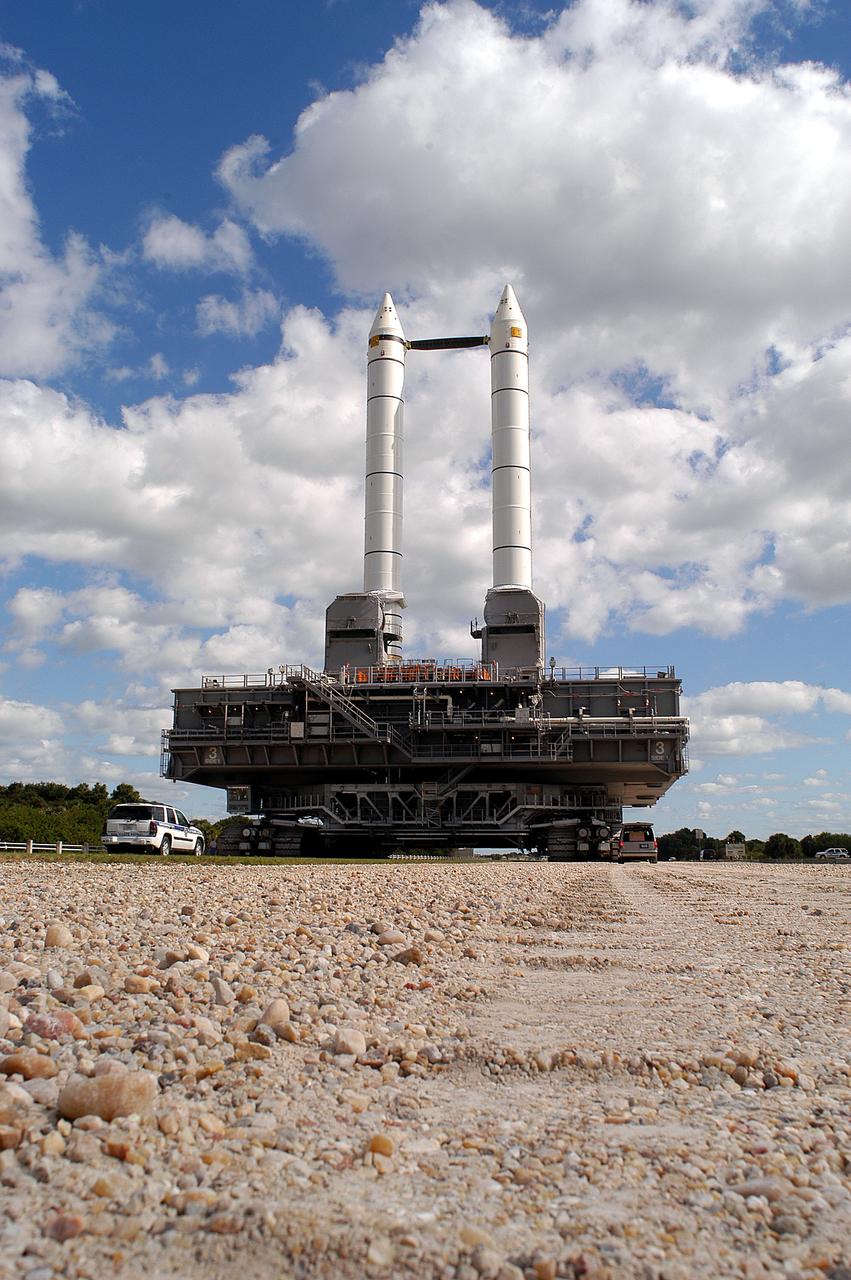 KENNEDY SPACE CENTER, FLA. -  Mobile Launcher Platform (MLP) number 3 and a set of twin solid rocket boosters, atop the crawler-transporter, inch along the crawlerway in support of the second engineering analysis vibration test on the crawler and MLP. The view reveals the river gravel surface that is 4 inches thick on the straightaway sections and 8 inches thick on curves. The crawler is moving at various speeds up to 1 mph in an effort to achieve vibration data gathering goals as it leaves the VAB, travels toward Launch Pad 39A and then returns.  The boosters are braced at the top for stability.  The primary purpose of these rollout tests is to gather data to develop future maintenance requirements on the transport equipment and the flight hardware. Various parts of the MLP and crawler transporter have been instrumented with vibration data collection equipment.