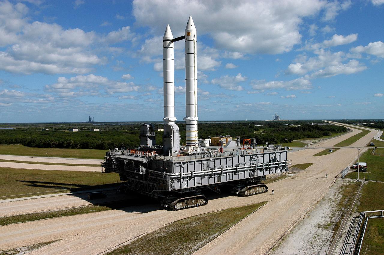 KENNEDY SPACE CENTER, FLA. -  Mobile Launcher Platform (MLP) number 3 and a set of twin solid rocket boosters bolted to it, atop the crawler-transporter, crawl to the intersection in the crawlerway in support of the second engineering analysis vibration test on the crawler and MLP.  In the background are Launch Pads 39A (right) and 39B (left).  The crawler is moving at various speeds up to 1 mph in an effort to achieve vibration data gathering goals as it leaves the VAB, travels toward Launch Pad 39A and then returns.  The boosters are braced at the top for stability.  The primary purpose of these rollout tests is to gather data to develop future maintenance requirements on the transport equipment and the flight hardware. Various parts of the MLP and crawler transporter have been instrumented with vibration data collection equipment.