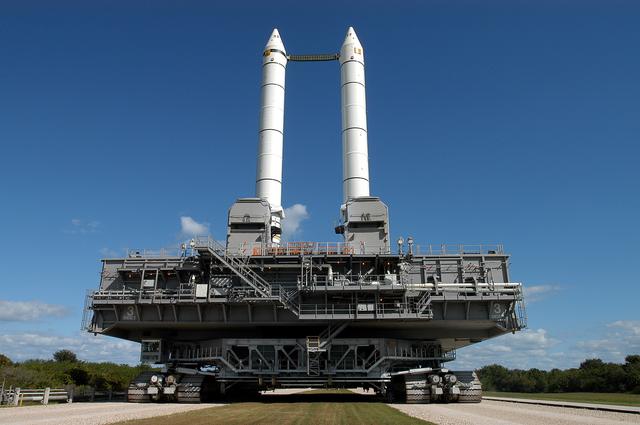 NASA image: KENNEDY SPACE CENTER, FLA. -  Like candles embedded in a sculptured “cake,” the Mobile Launcher Platform (MLP) number 3 with twin solid rocket boosters bolted to it inches along the crawlerway at various speeds up to 1 mph in an effort to achieve vibration data gathering goals. The boosters are braced at the top for stability.  The primary purpose of these rollout tests is to gather data to develop future maintenance requirements on the transport equipment and the flight hardware. Various parts of the MLP and crawler transporter have been instrumented with vibration data collection equipment.