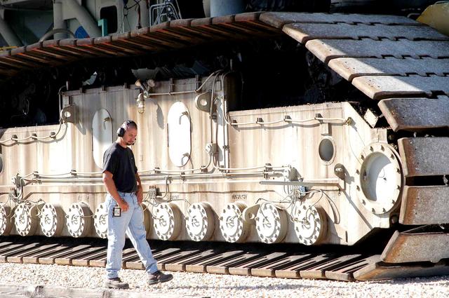 NASA image: KENNEDY SPACE CENTER, FLA. - A Kennedy Space Center technician walks towards the intersection of the crawlerway beside a crawler-transporter moving Mobile Launcher Platform (MLP) number 3, with a set of twin solid rocket boosters bolted atop, during the second engineering analysis vibration test on the crawler and MLP.  The crawler is moving at various speeds up to 1 mph in an effort to achieve vibration data gathering goals as it leaves the VAB, travels toward Launch Pad 39A, and then returns. The boosters are braced at the top for stability. The primary purpose of these rollout tests is to gather data to develop future maintenance requirements on the transport equipment and the flight hardware. Various parts of the MLP and crawler transporter have been instrumented with vibration data collection equipment.