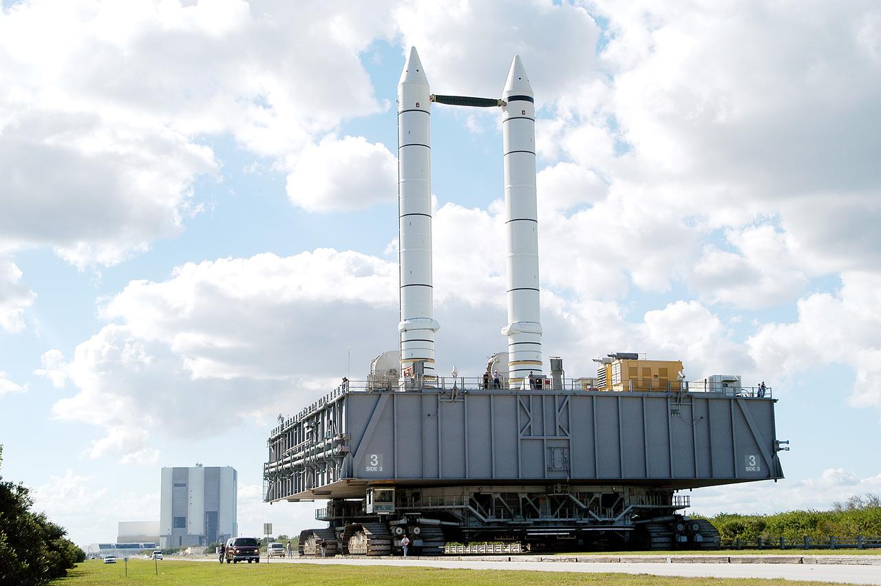 KENNEDY SPACE CENTER, FLA. - The crawler-transporter carrying Mobile Launcher Platform (MLP) number 3, with a set of twin solid rocket boosters bolted atop, crawls to the intersection in the crawlerway in support of the second engineering analysis vibration test on the crawler and MLP.  From this perspective, the Launch Control Center (left) and the 525-foot-tall Vehicle Assembly Building (right) in the background appear dwarfed by the 184-foot-tall boosters. The crawler is moving at various speeds up to 1 mph in an effort to achieve vibration data gathering goals as it leaves the VAB, travels toward Launch Pad 39A and then returns. The boosters are braced at the top for stability. The primary purpose of these rollout tests is to gather data to develop future maintenance requirements on the transport equipment and the flight hardware. Various parts of the MLP and crawler transporter have been instrumented with vibration data collection equipment.