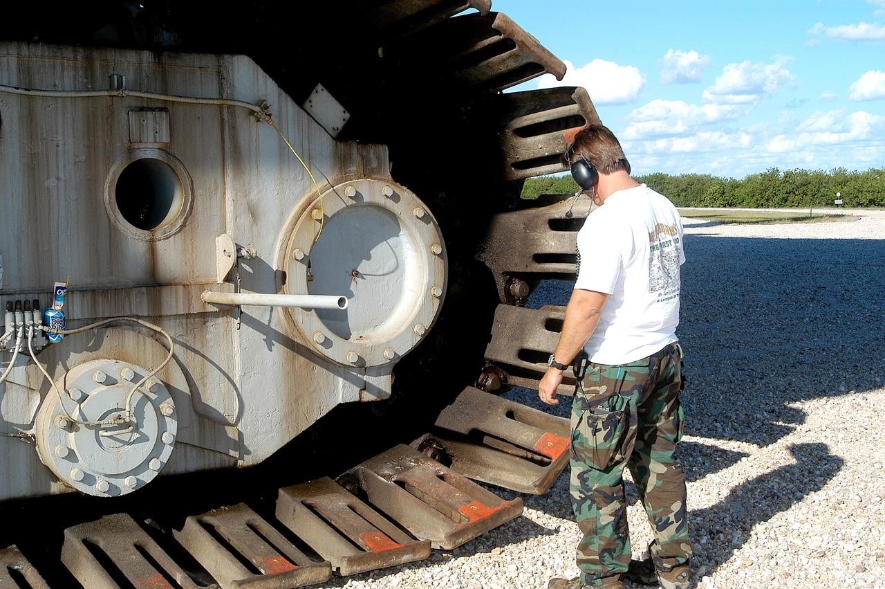 KENNEDY SPACE CENTER, FLA. - A Kennedy Space Center technician inspects the shoes on one of eight tracks of a crawler-transporter (CT).  The CT is moving Mobile Launcher Platform (MLP) number 3 with a set of twin solid rocket boosters bolted on top to the intersection in the crawlerway in support of the second engineering analysis vibration test on the crawler and MLP.  The crawler is moving at various speeds up to 1 mph in an effort to achieve vibration data gathering goals as it leaves the VAB, travels toward Launch Pad 39A and then returns. The boosters are braced at the top for stability. The primary purpose of these rollout tests is to gather data to develop future maintenance requirements on the transport equipment and the flight hardware. Various parts of the MLP and crawler transporter have been instrumented with vibration data collection equipment.