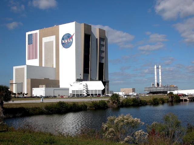 NASA image: KENNEDY SPACE CENTER, FLA. - Seen across the water of the Launch Complex 39 turn basin, a crawler-transporter, carrying Mobile Launcher Platform (MLP) number 3 with a set of twin solid rocket boosters bolted atop, crawls out of the 525-foot-tall Vehicle Assembly Building during the second engineering analysis vibration test on the crawler and MLP.  The crawler is moving at various speeds up to 1 mph in an effort to achieve vibration data gathering goals as it leaves the VAB, travels toward Launch Pad 39A and then returns. The boosters are braced at the top for stability. The primary purpose of these rollout tests is to gather data to develop future maintenance requirements on the transport equipment and the flight hardware. Various parts of the MLP and crawler transporter have been instrumented with vibration data collection equipment.