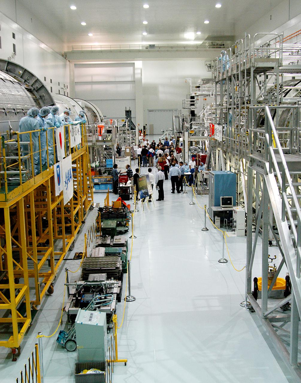 The Japanese Experiment Module or JEM (first element in left row), and other hardware undergoing processing for transport to the International Space Station, are made available for viewing by the media, assembling in the aisle of the Space Station Processing Facility (SSPF). Members of the media were invited to commemorate the fifth anniversary of the launch of the first element of the International Space Station by touring the SSPF. Reporters had the opportunity to see Space Station hardware that is being processed for deployment once the Space Shuttles return to flight, as well as talk with NASA and Boeing mission managers about the various hardware elements currently being processed for flight.