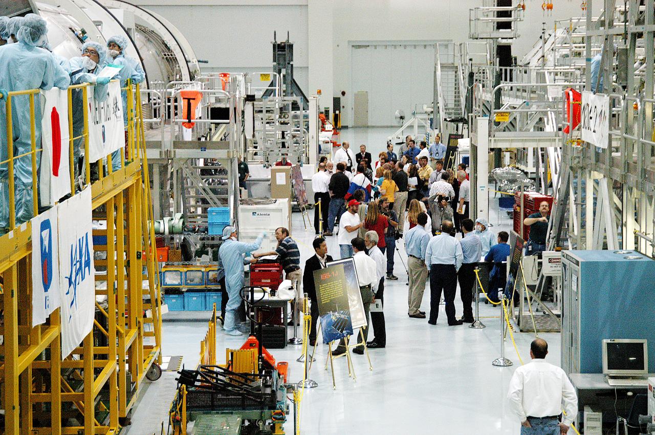 The Japanese Experiment Module or JEM (first element in left row), the Node 2 (first element in right row), and other hardware undergoing processing for transport to the International Space Station, are made available for viewing by the media, assembling in the aisle of the Space Station Processing Facility (SSPF). Members of the media were invited to commemorate the fifth anniversary of the launch of the first element of the International Space Station by touring the SSPF. Reporters had the opportunity to see Space Station hardware that is being processed for deployment once the Space Shuttles return to flight, as well as talk with NASA and Boeing mission managers about the various hardware elements currently being processed for flight.