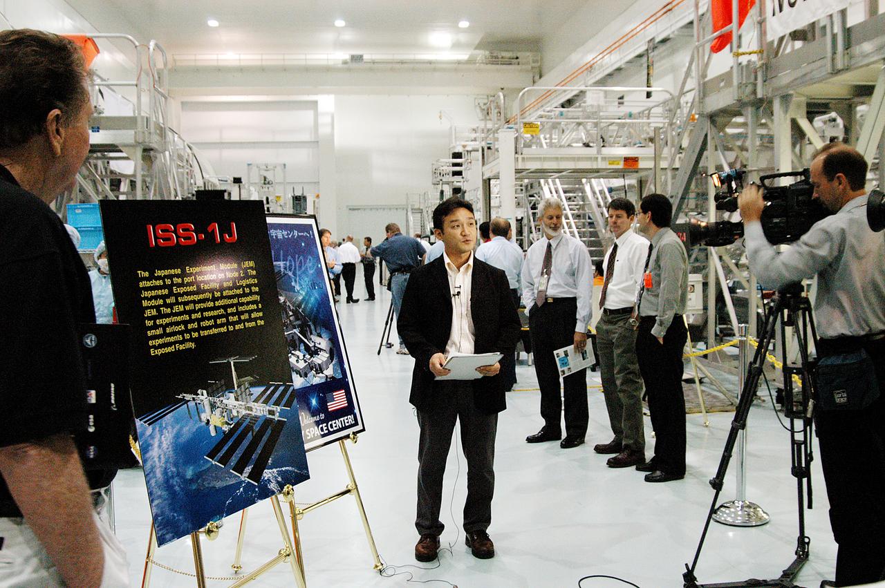 Members of the media were invited to commemorate the fifth anniversary of the launch of the first element of the International Space Station by touring the Space Station Processing Facility (SSPF) at KSC. Here, Shimpei Takahashi (center), representative of the Japanese Air and Space Agency (JAXA), talks about the Japanese Experiment Module (JEM) on camera. Reporters had the opportunity to see Space Station hardware that is being processed for deployment once the Space Shuttles return to flight, as well as talk with NASA and Boeing mission managers about the various hardware elements currently being processed for flight.