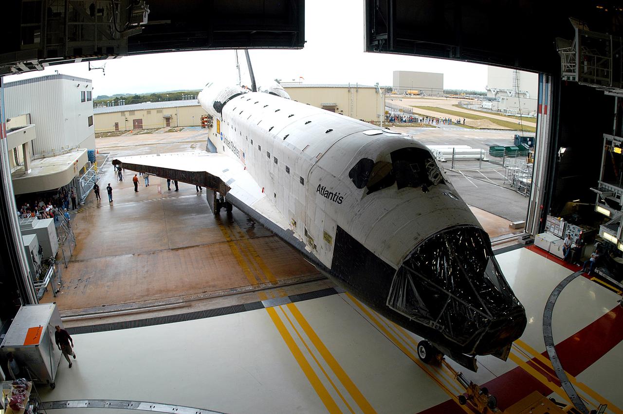 KENNEDY SPACE CENTER, FLA. - The Space Shuttle orbiter Atlantis backs out of the Orbiter Processing Facility (OPF) for its move to the Vehicle Assembly Building (VAB). The move will allow work to be performed in the OPF that can only be accomplished while the bay is empty. Work scheduled in the processing facility includes annual validation of the bay's cranes, work platforms, lifting mechanisms, and jack stands. Atlantis will remain in the VAB for about 10 days, then return to the OPF as work resumes to prepare it for launch in September 2004 on the first return-to-flight mission, STS-114.