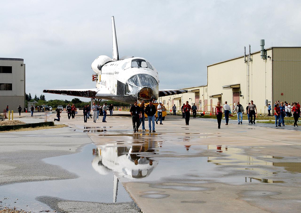 KENNEDY SPACE CENTER, FLA. - The Space Shuttle orbiter Atlantis is reflected in a rain puddle as it is towed from the Orbiter Processing Facility (OPF) to the Vehicle Assembly Building (VAB). The move will allow work to be performed in the OPF that can only be accomplished while the bay is empty. Work scheduled in the processing facility includes annual validation of the bay's cranes, work platforms, lifting mechanisms, and jack stands. Atlantis will remain in the VAB for about 10 days, then return to the OPF as work resumes to prepare it for launch in September 2004 on the first return-to-flight mission, STS-114.