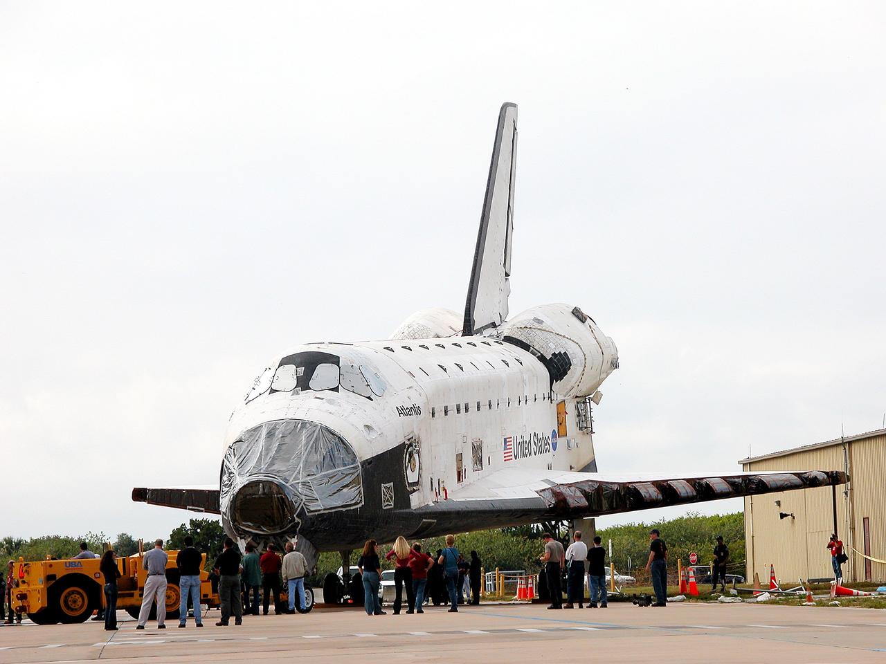 KENNEDY SPACE CENTER, FLA. - Workers walk with Space Shuttle orbiter Atlantis from the Orbiter Processing Facility (OPF) to the Vehicle Assembly Building (VAB) high bay 4. The move will allow work to be performed in the OPF that can only be accomplished while the bay is empty. Work scheduled in the processing facility includes annual validation of the bay's cranes, work platforms, lifting mechanisms, and jack stands. Atlantis will remain in the VAB for about 10 days, then return to the OPF as work resumes to prepare it for launch in September 2004 on the first return-to-flight mission, STS-114.