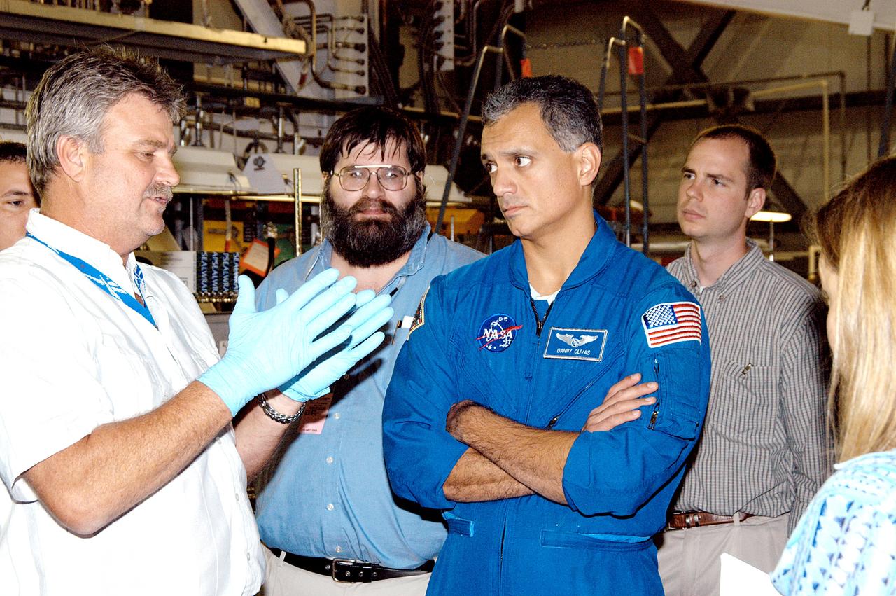 KENNEDY SPACE CENTER, FLA. -  - In the Orbiter Processing Facility astronaut Danny Olivas listens to Greg Grantham (left) talking about the Reinforced Carbon Carbon panels used on the leading edge of the wing of the orbiters.  Behind Olivas are engineers from around the Agency who are working on improving the RCC panels used on the wing leading edge. The gray carbon composite RCC panels have sufficient strength to withstand the aerodynamic forces experienced during launch and reentry, which can reach as high as 800 pounds per square foot.  The operating range of RCC is from minus 250º F to about 3,000º F, the temperature produced by friction with the atmosphere during reentry.