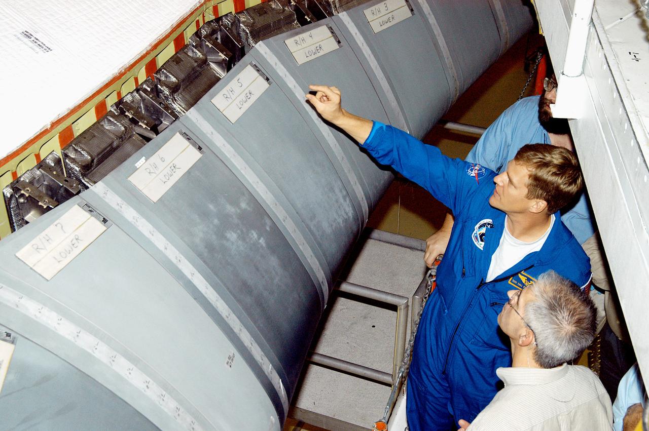 KENNEDY SPACE CENTER, FLA. -  In the Orbiter Processing Facility, astronaut Scott E. Parazynski points to the Reinforced Carbon Carbon panels used on the leading edge of the wing of the orbiters. With Parazynski are engineers from around the Agency who are working on improving the RCC panels used on the wing leading edge.  The gray carbon composite RCC panels have sufficient strength to withstand the aerodynamic forces experienced during launch and reentry, which can reach as high as 800 pounds per square foot.  The operating range of RCC is from minus 250º F to about 3,000º F, the temperature produced by friction with the atmosphere during reentry.