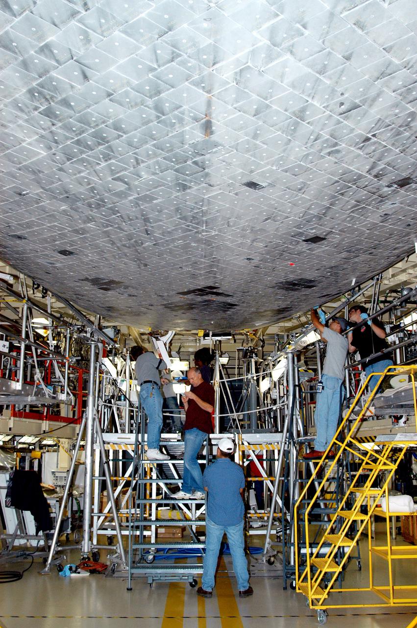 KENNEDY SPACE CENTER, FLA. -  In the Orbiter Processing Facility, KSC technicians work on the underbody of the orbiter Discovery.  The vehicle has undergone Orbiter Major Modifications in the past year.  Discovery is scheduled to fly on mission STS-121 to the International Space Station.