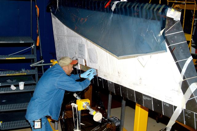 NASA image: KENNEDY SPACE CENTER, FLA. -  In the Orbiter Processing Facility, KSC employee Joel Smith prepares an area on the orbiter Discovery for blanket installation.  The blankets are part of the Orbiter Thermal Protection System, thermal shields to protect against temperatures as high as 3,000° Fahrenheit, which are produced during descent for landing. Discovery is scheduled to fly on mission STS-121 to the International Space Station.