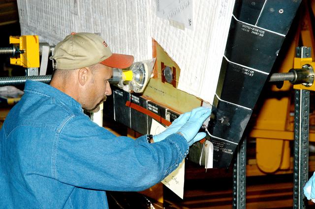 NASA image: KENNEDY SPACE CENTER, FLA. -  In the Orbiter Processing Facility, KSC employee Joel Smith prepares an area on the orbiter Discovery for blanket installation.  The blankets are part of the Orbiter Thermal Protection System, thermal shields to protect against temperatures as high as 3,000° Fahrenheit, which are produced during descent for landing. Discovery is scheduled to fly on mission STS-121 to the International Space Station.