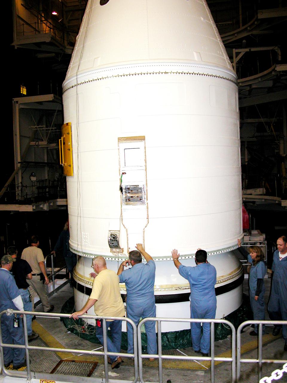 KENNEDY SPACE CENTER, FLA. -  In the Vehicle Assembly Building, KSC employees help guide the destacking of the forward assembly (nose cap and frustum) from a solid rocket booster (SRB) after the bolts were removedThe destacking is part of time and cycle activities.  The SRB was part of the stack on Atlantis originally scheduled for a March 1, 2003, launch on mission STS-114.  The SRBs and external tank were demated in February 2003.   The mission is now scheduled to occur no earlier than Sept. 12, 2004, on Atlantis.