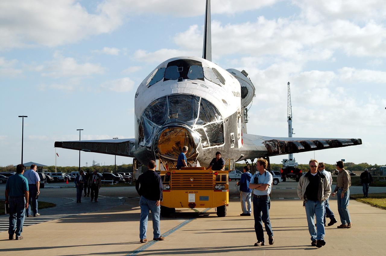 KENNEDY SPACE CENTER, FLA. -  Workers accompany the orbiter Atlantis as it is towed back to the Orbiter Processing Facility after spending 10 days in the Vehicle Assembly Building.  The hiatus in the VAB allowed work to be performed in the OPF that can only be accomplished while the bay is empty. Work included annual validation of the bay's cranes, work platforms, lifting mechanisms and jack stands.  Work resumes to prepare Atlantis for launch in September 2004 on the first return-to-flight mission, STS-114.