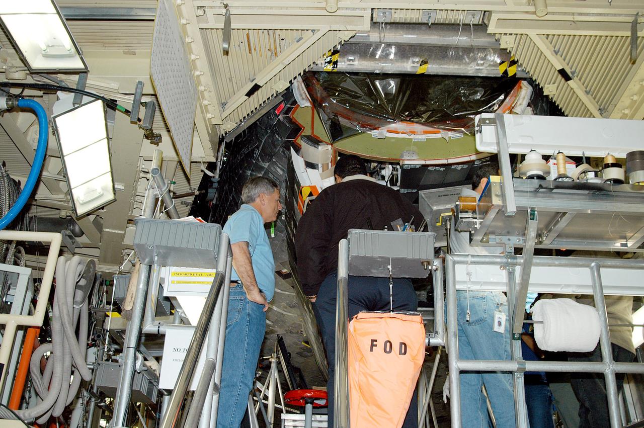 KENNEDY SPACE CENTER, FLA. -- NASA Deputy Associate Administrator for Space Station and Shuttle Programs Michael Kostelnik (left) discusses some of the working parts inside the nose of Shuttle Discovery in Orbiter Processing Facility Bay 3 with a United Space Alliance (USA) technician (back to camera).  NASA and USA Space Shuttle program management are participating in a leadership workday.  The day is intended to provide management with an in-depth, hands-on look at Shuttle processing activities at KSC.