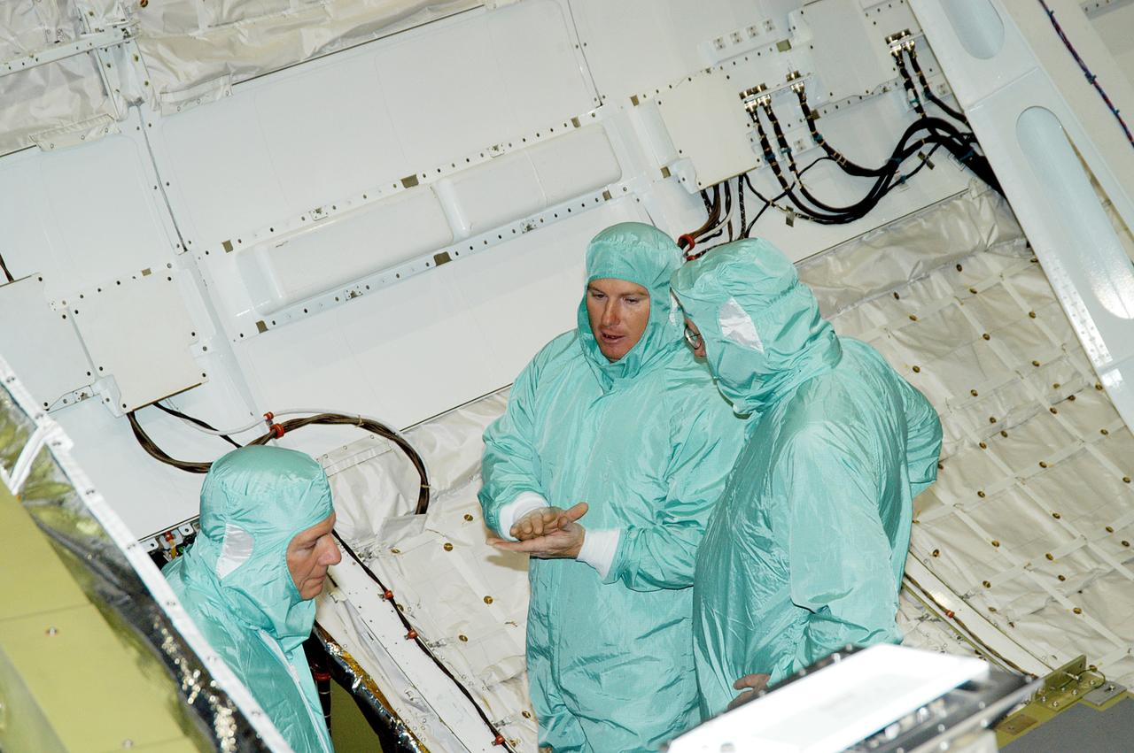 KENNEDY SPACE CENTER, FLA. -- In Orbiter Processing Facility Bay 1, NASA Deputy Associate Administrator for Space Station and Shuttle Programs Michael Kostelnik (left) and United Space Alliance (USA) Vice President and Space Shuttle Program Manager Howard DeCastro (right) are briefed by a USA technician (center) on Shuttle processing in the payload bay of orbiter Atlantis.  NASA and USA Space Shuttle program management are participating in a leadership workday.  The day is intended to provide management with an in-depth, hands-on look at Shuttle processing activities at KSC.