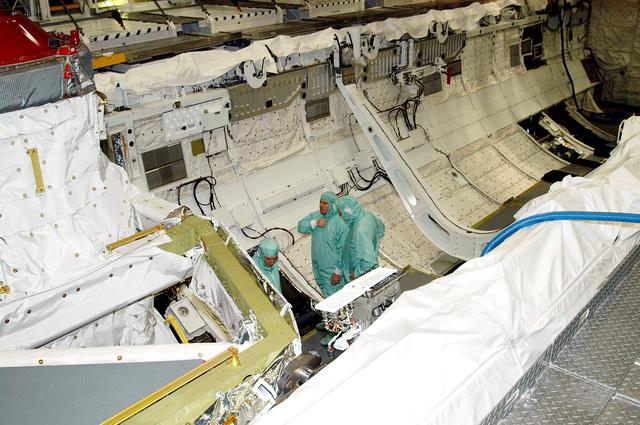 KENNEDY SPACE CENTER, FLA. -- In Orbiter Processing Facility Bay 1, NASA Deputy Associate Administrator for Space Station and Shuttle Programs Michael Kostelnik (left) and United Space Alliance (USA) Vice President and Space Shuttle Program Manager Howard DeCastro (right) are briefed by a USA technician (center) on Shuttle processing in the payload bay of orbiter Atlantis.  NASA and USA Space Shuttle program management are participating in a leadership workday.  The day is intended to provide management with an in-depth, hands-on look at Shuttle processing activities at KSC.