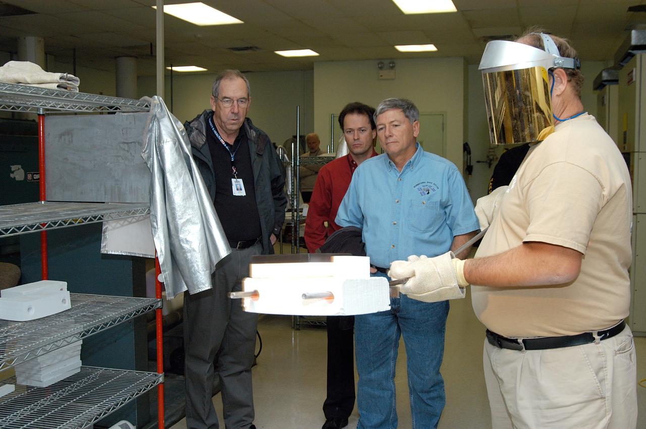 KENNEDY SPACE CENTER, FLA. -- United Space Alliance (USA) Vice President and Space Shuttle Program Manager Howard DeCastro (left) and NASA Deputy Associate Administrator for Space Station and Shuttle Programs Michael Kostelnik (third from left) watch as a USA technician (right) creates a tile for use in the Shuttle's Thermal Protection System (TPS).  NASA and USA Space Shuttle program management are participating in a leadership workday.  The day is intended to provide management with an in-depth, hands-on look at Shuttle processing activities at KSC.