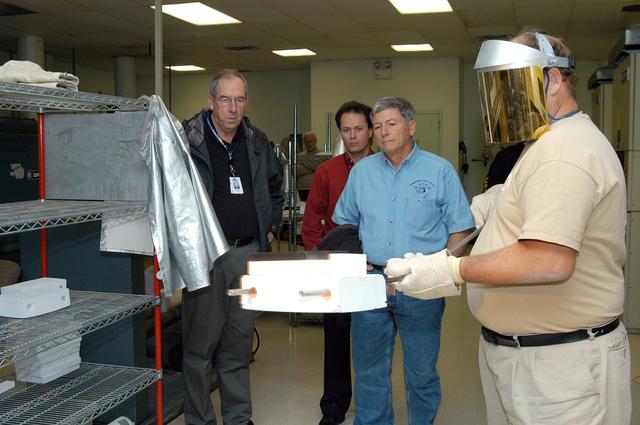NASA image: KENNEDY SPACE CENTER, FLA. -- United Space Alliance (USA) Vice President and Space Shuttle Program Manager Howard DeCastro (left) and NASA Deputy Associate Administrator for Space Station and Shuttle Programs Michael Kostelnik (third from left) watch as a USA technician (right) creates a tile for use in the Shuttle's Thermal Protection System (TPS).  NASA and USA Space Shuttle program management are participating in a leadership workday.  The day is intended to provide management with an in-depth, hands-on look at Shuttle processing activities at KSC.