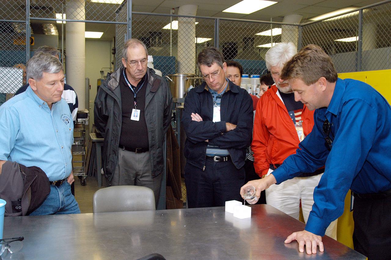 KENNEDY SPACE CENTER, FLA. -- From left, NASA Deputy Associate Administrator for Space Station and Shuttle Programs Michael Kostelnik and United Space Alliance (USA) Vice President and Space Shuttle Program Manager Howard DeCastro are briefed on the properties of the tile used in the Shuttle's Thermal Protection System (TPS) by USA Manager of the TPS Facility Martin Wilson (right).  NASA and USA Space Shuttle program management are participating in a leadership workday.  The day is intended to provide management with an in-depth, hands-on look at Shuttle processing activities at KSC.