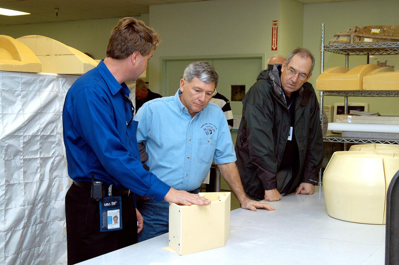KENNEDY SPACE CENTER, FLA. -- From left, United Space Alliance (USA) Manager of the Thermal Protection System (TPS) Facility Martin Wilson briefs NASA Deputy Associate Administrator for Space Station and Shuttle Programs Michael Kostelnik and USA Vice President and Space Shuttle Program Manager Howard DeCastro on aspects of creating the tile used in the Shuttle's TPS. NASA and USA Space Shuttle program management are participating in a leadership workday. The day is intended to provide management with an in-depth, hands-on look at Shuttle processing activities at KSC.