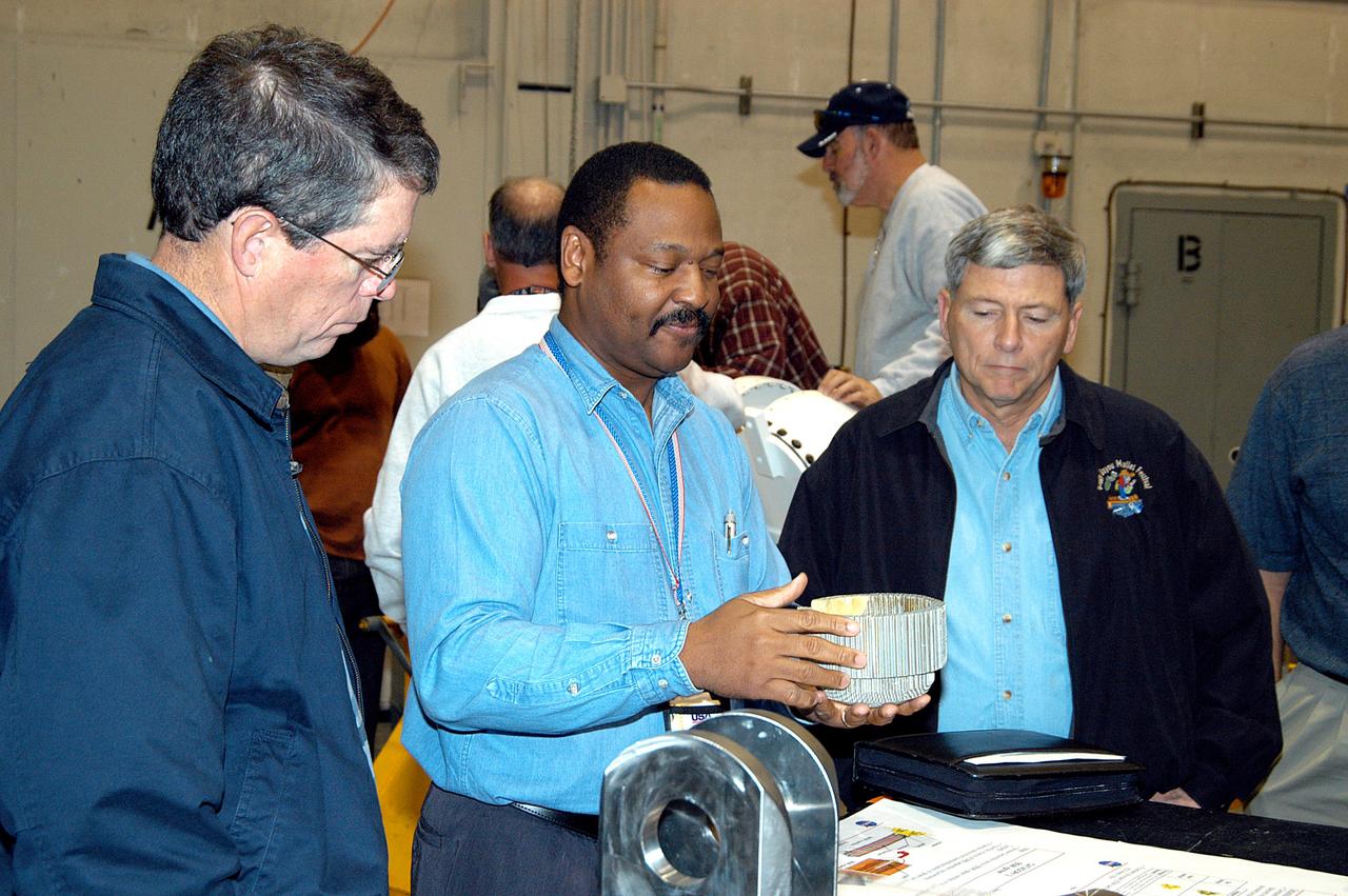 KENNEDY SPACE CENTER, FLA. -- A United Space Alliance (USA) technician (center) discusses aspects of Shuttle processing performed in the Solid Rocket Booster (SRB) Assembly and Refurbishment Facility (ARF) with NASA Deputy Associate Administrator for Space Station and Shuttle Programs Michael Kostelnik (right).  NASA and USA Space Shuttle program management are participating in a leadership workday.  The day is intended to provide management with an in-depth, hands-on look at Shuttle processing activities at KSC.