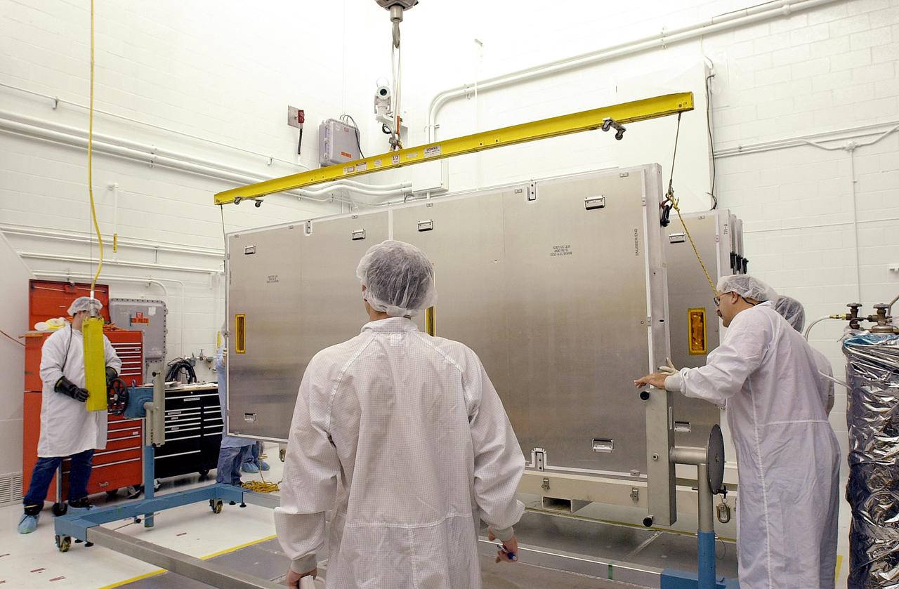 VANDENBERG AFB, CALIF. - Workers in the NASA spacecraft processing facility on North Vandenberg Air Force Base prepare to rotate the framework containing one of four solar panels to be installed on the Gravity Probe B spacecraft. Installing each array is a 3-day process and includes a functional deployment test. The Gravity Probe B mission is a relativity experiment developed by NASA’s Marshall Space Flight Center, Stanford University and Lockheed Martin. The spacecraft will test two extraordinary predictions of Albert Einstein’s general theory of relativity that he advanced in 1916: the geodetic effect (how space and time are warped by the presence of the Earth) and frame dragging (how Earth’s rotation drags space and time around with it). Gravity Probe B consists of four sophisticated gyroscopes that will provide an almost perfect space-time reference system. The mission will look in a precision manner for tiny changes in the direction of spin.