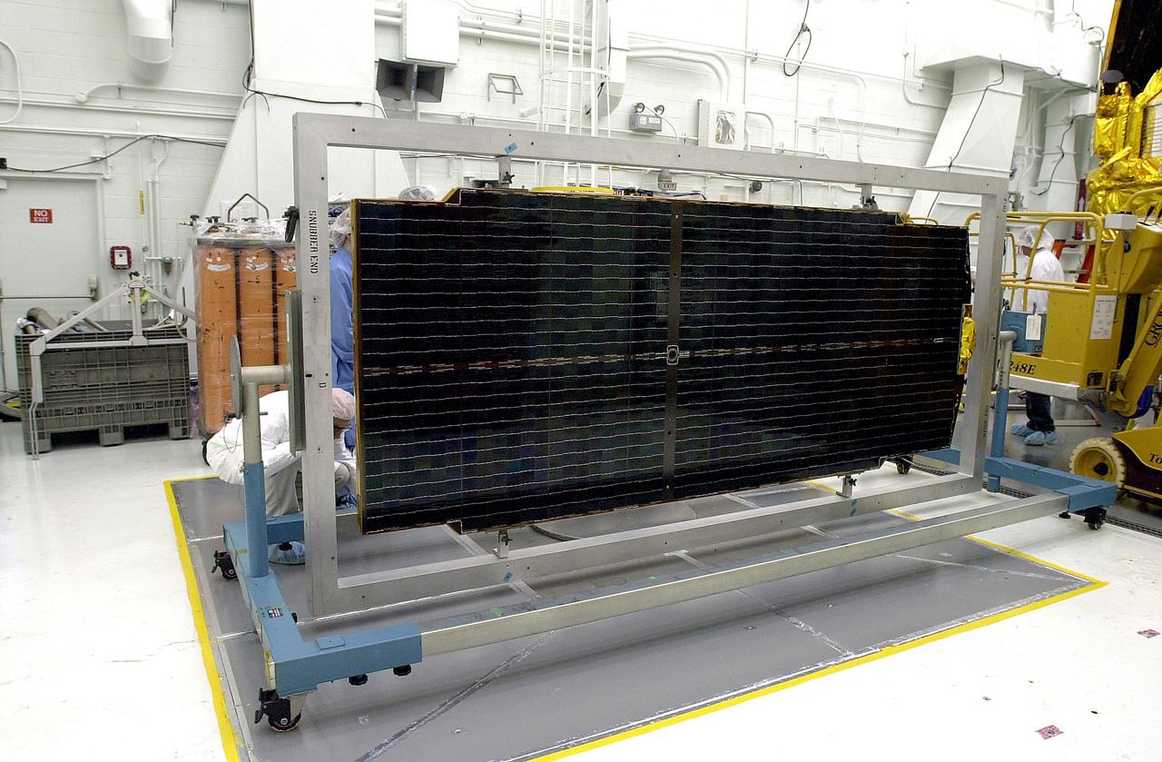 VANDENBERG AFB, CALIF. - Workers in the NASA spacecraft processing facility on North Vandenberg Air Force Base work on a solar array panel to be installed on the Gravity Probe B spacecraft. Installing each array is a 3-day process and includes a functional deployment test. The Gravity Probe B mission is a relativity experiment developed by NASA’s Marshall Space Flight Center, Stanford University and Lockheed Martin. The spacecraft will test two extraordinary predictions of Albert Einstein’s general theory of relativity that he advanced in 1916: the geodetic effect (how space and time are warped by the presence of the Earth) and frame dragging (how Earth’s rotation drags space and time around with it). Gravity Probe B consists of four sophisticated gyroscopes that will provide an almost perfect space-time reference system. The mission will look in a precision manner for tiny changes in the direction of spin.