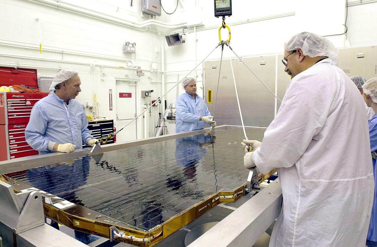 VANDENBERG AFB, CALIF. - Workers in the NASA spacecraft processing facility on North Vandenberg Air Force Base attach supports to a solar array panel to be lifted and installed on the Gravity Probe B spacecraft. Installing each array is a 3-day process and includes a functional deployment test. The Gravity Probe B mission is a relativity experiment developed by NASA’s Marshall Space Flight Center, Stanford University and Lockheed Martin. The spacecraft will test two extraordinary predictions of Albert Einstein’s general theory of relativity that he advanced in 1916: the geodetic effect (how space and time are warped by the presence of the Earth) and frame dragging (how Earth’s rotation drags space and time around with it). Gravity Probe B consists of four sophisticated gyroscopes that will provide an almost perfect space-time reference system. The mission will look in a precision manner for tiny changes in the direction of spin.
