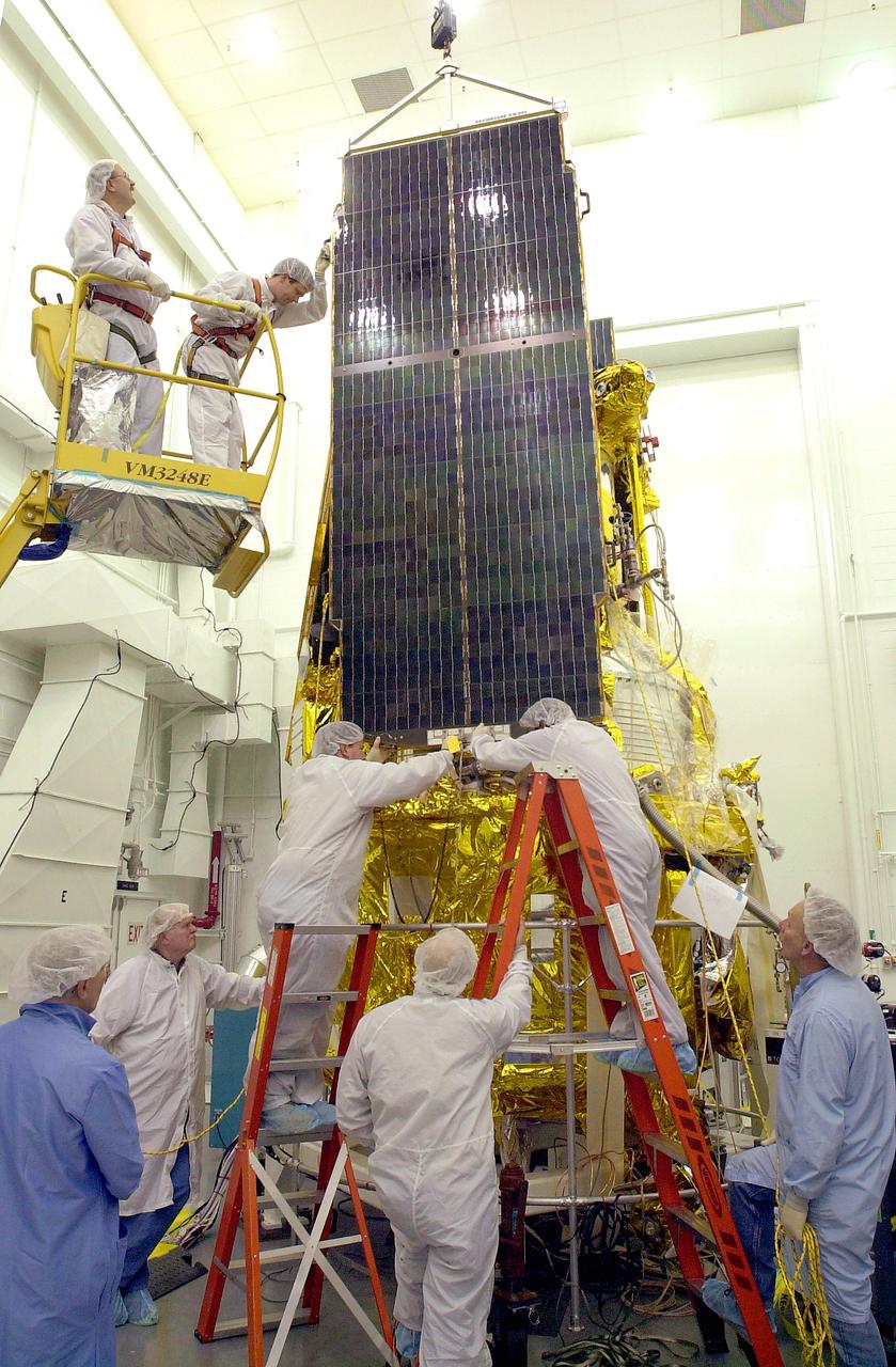 VANDENBERG AFB, CALIF. - Workers in the NASA spacecraft processing facility on North Vandenberg Air Force Base attach a solar array panel on the Gravity Probe B spacecraft. Installing each array is a 3-day process and includes a functional deployment test. The Gravity Probe B mission is a relativity experiment developed by NASA’s Marshall Space Flight Center, Stanford University and Lockheed Martin. The spacecraft will test two extraordinary predictions of Albert Einstein’s general theory of relativity that he advanced in 1916: the geodetic effect (how space and time are warped by the presence of the Earth) and frame dragging (how Earth’s rotation drags space and time around with it). Gravity Probe B consists of four sophisticated gyroscopes that will provide an almost perfect space-time reference system. The mission will look in a precision manner for tiny changes in the direction of spin.