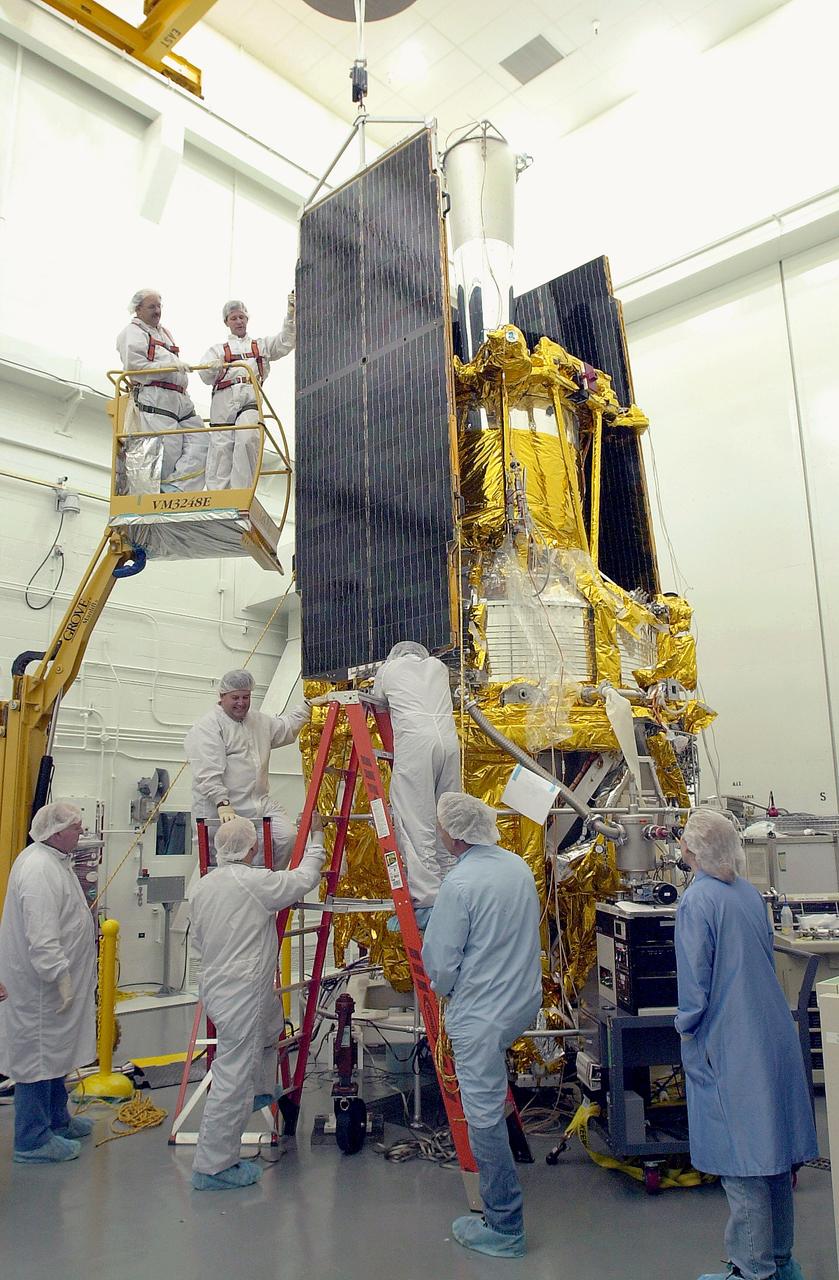 VANDENBERG AFB, CALIF. - Workers in the NASA spacecraft processing facility on North Vandenberg Air Force Base attach a solar array panel on the Gravity Probe B spacecraft. Installing each array is a 3-day process and includes a functional deployment test. The Gravity Probe B mission is a relativity experiment developed by NASA’s Marshall Space Flight Center, Stanford University and Lockheed Martin. The spacecraft will test two extraordinary predictions of Albert Einstein’s general theory of relativity that he advanced in 1916: the geodetic effect (how space and time are warped by the presence of the Earth) and frame dragging (how Earth’s rotation drags space and time around with it). Gravity Probe B consists of four sophisticated gyroscopes that will provide an almost perfect space-time reference system. The mission will look in a precision manner for tiny changes in the direction of spin.