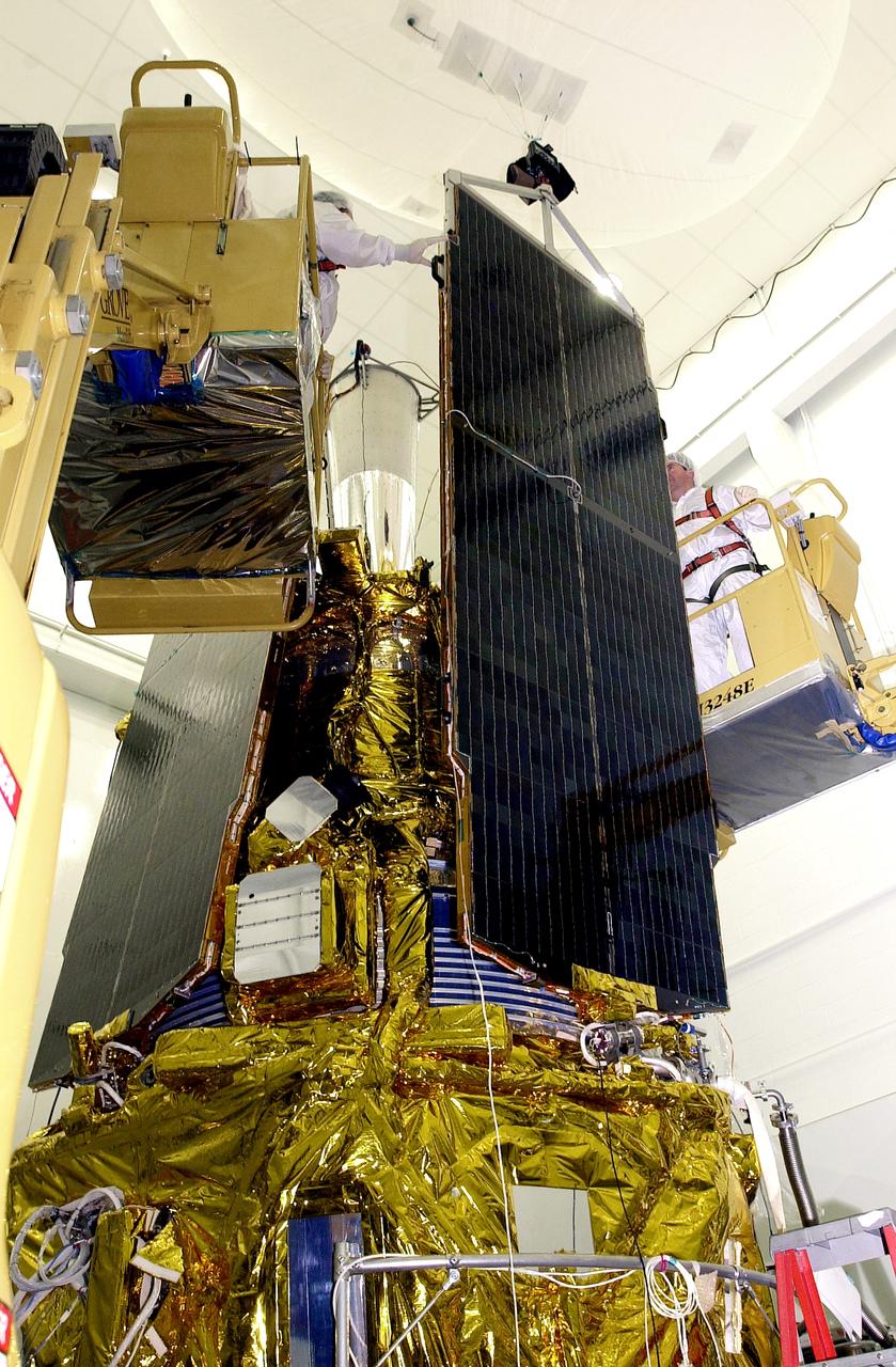 VANDENBERG AFB, CALIF. - In the NASA spacecraft processing facility on North Vandenberg Air Force Base, workers prepare to attach the top of a solar array panel onto the Gravity Probe B spacecraft. Installing each array is a 3-day process and includes a functional deployment test. The Gravity Probe B mission is a relativity experiment developed by NASA’s Marshall Space Flight Center, Stanford University and Lockheed Martin. The spacecraft will test two extraordinary predictions of Albert Einstein’s general theory of relativity that he advanced in 1916: the geodetic effect (how space and time are warped by the presence of the Earth) and frame dragging (how Earth’s rotation drags space and time around with it). Gravity Probe B consists of four sophisticated gyroscopes that will provide an almost perfect space-time reference system. The mission will look in a precision manner for tiny changes in the direction of spin.