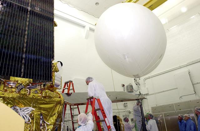 NASA image: VANDENBERG AFB, CALIF. -  In the NASA spacecraft processing facility on North Vandenberg Air Force Base, workers stand by as the balloon at right is released to lift the solar array panel into position for installation on the Gravity Probe B spacecraft.  Installing each array is a 3-day process and includes a functional deployment test.  The Gravity Probe B mission is a relativity experiment developed by NASA’s Marshall Space Flight Center, Stanford University and Lockheed Martin.  The spacecraft will test two extraordinary predictions of Albert Einstein’s general theory of relativity that he advanced in 1916: the geodetic effect (how space and time are warped by the presence of the Earth) and frame dragging (how Earth’s rotation drags space and time around with it).  Gravity Probe B consists of four sophisticated gyroscopes that will provide an almost perfect space-time reference system.  The mission will look in a precision manner for tiny changes in the direction of spin.