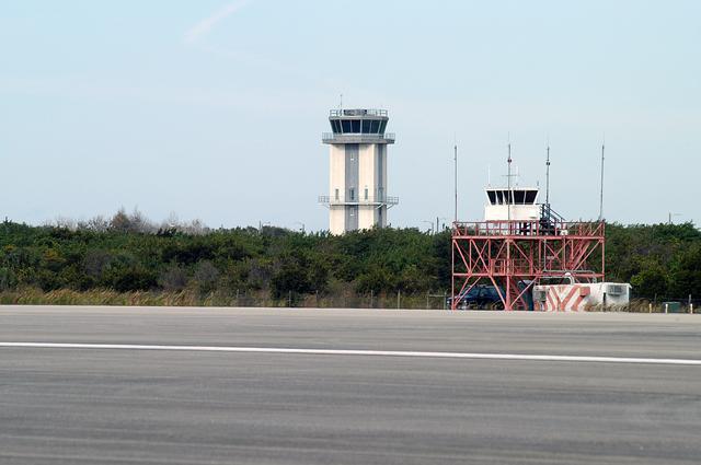 NASA image: KENNEDY SPACE CENTER, FLA. -- Two control towers are seen at the edge of the KSC Shuttle Landing Facility, the old one in front and the nearly completed new tower in back.  The old tower stands only 20 feet above the runway surface, too low to see the launch pads to the east. During nighttime landing operations, those inside the tower have been hindered by the eight-billion candlepower xenon lights that illuminate the runway.  The new control tower is built atop an existing mound, rising nearly 100 feet over the midpoint of the runway.  The height gives controllers a spectacular 360-degree view of NASA-KSC and northern Brevard County. The new facility will also replace the SLF Operations Building. The operations building is home to the Military Radar Unit that monitors NASA-KSC airspace 24 hours a day, as well as runway light controls, navigational aids, weather and wind speed instrumentation, and gate controls. In the new tower, the computer displays will be fully modernized to Federal Aviation Administration standards with touch-screen technology. Construction on the new facility began in February 2003 and is nearly ready for occupancy. Only some final inspections and approvals remain. A support building and Public Affairs viewing deck, to be used for observing future landing operations, will be added and are already in work.