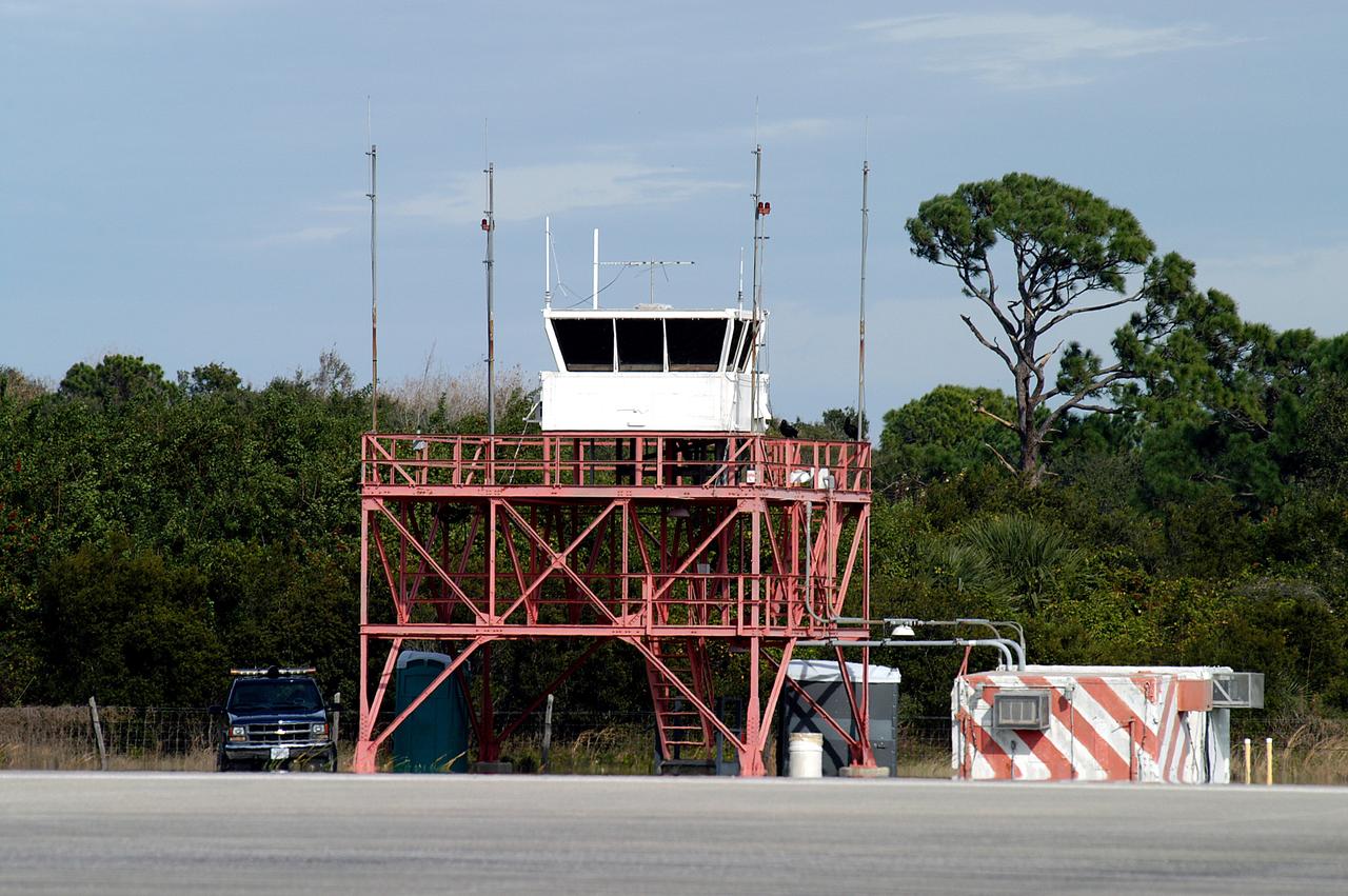 KENNEDY SPACE CENTER, FLA. -- The existing control tower seen here at the edge of the KSC Shuttle Landing Facility is being replaced.  In use since 1987, the old tower stands only 20 feet above the runway surface, too low to see the launch pads to the east. During nighttime landing operations, those inside the tower have been hindered by the eight-billion candlepower xenon lights that illuminate the runway.  The new control tower is built atop an existing mound, rising nearly 100 feet over the midpoint of the runway.  The height gives controllers a spectacular 360-degree view of NASA-KSC and northern Brevard County. The new facility will also replace the SLF Operations Building. The operations building is home to the Military Radar Unit that monitors NASA-KSC airspace 24 hours a day, as well as runway light controls, navigational aids, weather and wind speed instrumentation, and gate controls. In the new tower, the computer displays will be fully modernized to Federal Aviation Administration standards with touch-screen technology. Construction on the new facility began in February 2003 and is nearly ready for occupancy. Only some final inspections and approvals remain. A support building and Public Affairs viewing deck, to be used for observing future landing operations, will be added and are already in work.