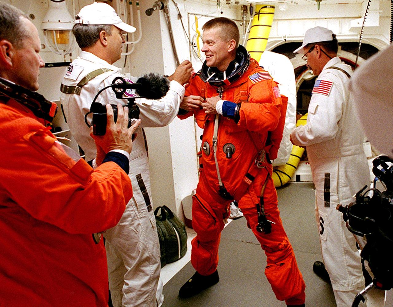 KENNEDY SPACE CENTER, FLA. - STS-107 Pilot William "Willie" McCool (center) gets help with his launch and entry suit from the Closeout Crew in the White Room. The environmentally controlled chamber is mated to Space Shuttle Columbia for entry into the Shuttle. In the foreground, left, is Mission Specialist David Brown. STS-107 is a mission devoted to research and will include more than 80 experiments that will study Earth and space science, advanced technology development, and astronaut health and safety. The payload on Space Shuttle Columbia includes FREESTAR (Fast Reaction Experiments Enabling Science, Technology, Applications and Research) and the SHI Research Double Module (SHI/RDM), known as SPACEHAB. Experiments on the module range from material sciences to life sciences. Liftoff is scheduled for 10:39 a.m. EST.