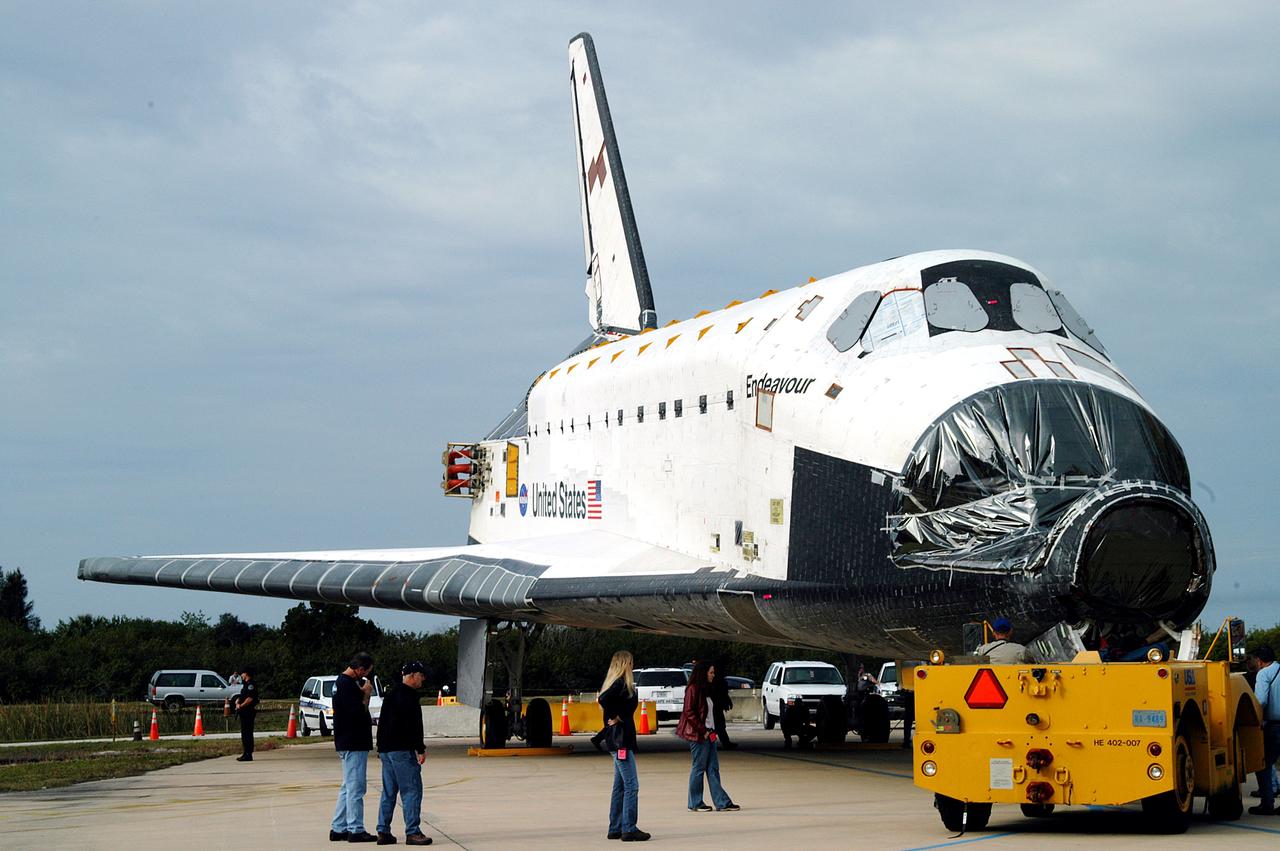 KENNEDY SPACE CENTER, FLA. -- After Endeavour’s rollout from inside the Orbiter Processing Facility, the transporter (foreground) prepares to tow it to the Vehicle Assembly Building for temporary transfer.  A protective cover surrounds the nose of Endeavour.  The move to the VAB allows work to be performed in the OPF that can only be accomplished while the bay is empty. Work scheduled in the OPF includes annual validation of the bay’s cranes, work platforms, lifting mechanisms and jack stands. Endeavour will remain in the VAB for approximately 12 days, then return to the OPF.
