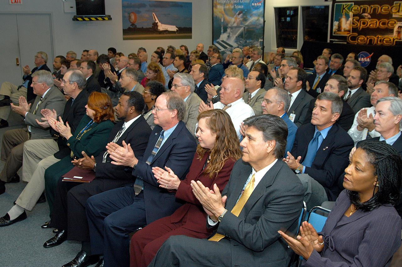 KENNEDY SPACE CENTER, FLA. -- In the KSC television studio, KSC management and other employees applaud President George W. Bush, who addressed the public and an assembly of government officials at NASA Headquarters as he outlined a new focus and vision for the space agency. Seated in the front row, left to right, are Bill Pickavance vice president and associate program manager of Florida Operations, United Space Alliance (USA) ; Howard DeCastro, vice president and Space Shuttle program manager, USA; Shannon Roberts, with External Affairs; Woodrow Whitlow, KSC deputy director; Bruce Buckingham, assistant to Dr. Whitlow; Lisa Malone, director of External Affairs; Ken Aguilar, chief, Equal Opportunity office; and Cheryl Cox, External Affairs. The President stated his goals for NASA’s new mission: Completing the International Space Station, retiring the Space Shuttle orbiters, developing a new crew exploration vehicle, and returning to the moon and beyond within the next two decades. Pres. Bush was welcomed by NASA Administrator Sean O’Keefe and Expedition 8 Commander Michael Foale, who greeted him from the International Space Station. Members of the Washington, D.C., audience included astronauts Eileen Collins, Ed Lu and Michael Lopez-Alegria, and former astronaut Gene Cernan.