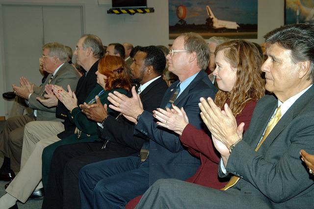 NASA image: KENNEDY SPACE CENTER, FLA. -- In the KSC television studio, KSC management and other employees applaud President George W. Bush, who addressed the public and an assembly of government officials at NASA Headquarters as he outlined a new focus and vision for the space agency.  Seated in the front row, left to right, are Bill Pickavance vice president and associate program manager of Florida Operations, United Space Alliance (USA) ; Howard DeCastro, vice president and Space Shuttle program manager, USA; Shannon Roberts, with External Affairs; Woodrow Whitlow, KSC deputy director; Bruce Buckingham, assistant to Dr. Whitlow; Lisa Malone, director of External Affairs; and Ken Aguilar, chief, Equal Opportunity office.  The President stated his goals for NASA’s new mission: Completing the International Space Station, retiring the Space Shuttle orbiters, developing a new crew exploration vehicle, and returning to the moon and beyond within the next two decades.   Pres. Bush was welcomed by NASA Administrator Sean O’Keefe and Expedition 8 Commander Michael Foale, who greeted him from the International Space Station.  Members of the Washington, D.C., audience included astronauts Eileen Collins, Ed Lu and Michael Lopez-Alegria, and former astronaut Gene Cernan.