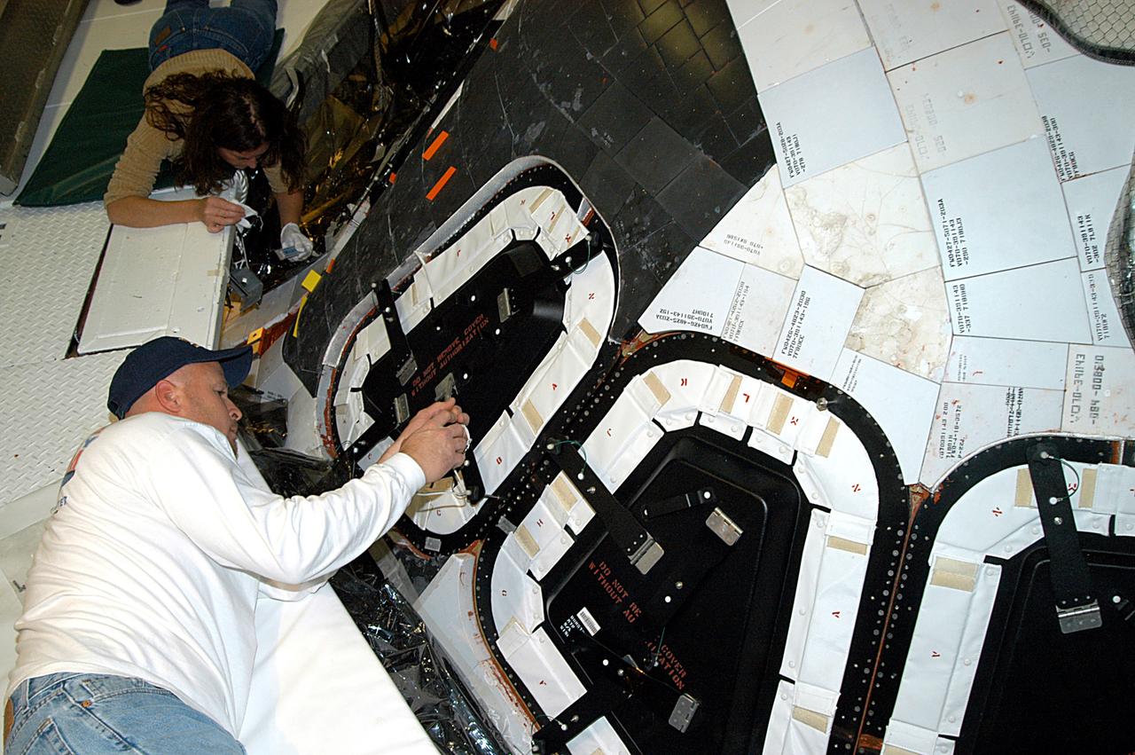 KENNEDY SPACE CENTER, FLA. -- Les Hanks (foreground) and Darlene Beville (background), with United Space Alliance,  prepare a window on Atlantis for removal.  The windows are being removed to inspect them for contaminants in the thermal seal.  Atlantis has been undergoing routine maintenance in the Orbiter Processing Facility for Return to Flight, on mission STS-114.
