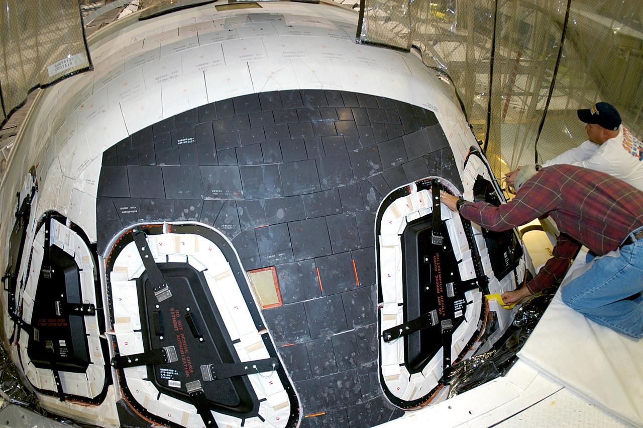 KENNEDY SPACE CENTER, FLA. -- At right, Mike Young and Les Hanks, with United Space Alliance, prepare a window on Atlantis for removal.  The windows are being removed to inspect them for contaminants in the thermal seal.  Atlantis has been undergoing routine maintenance in the Orbiter Processing Facility for Return to Flight, on mission STS-114.
