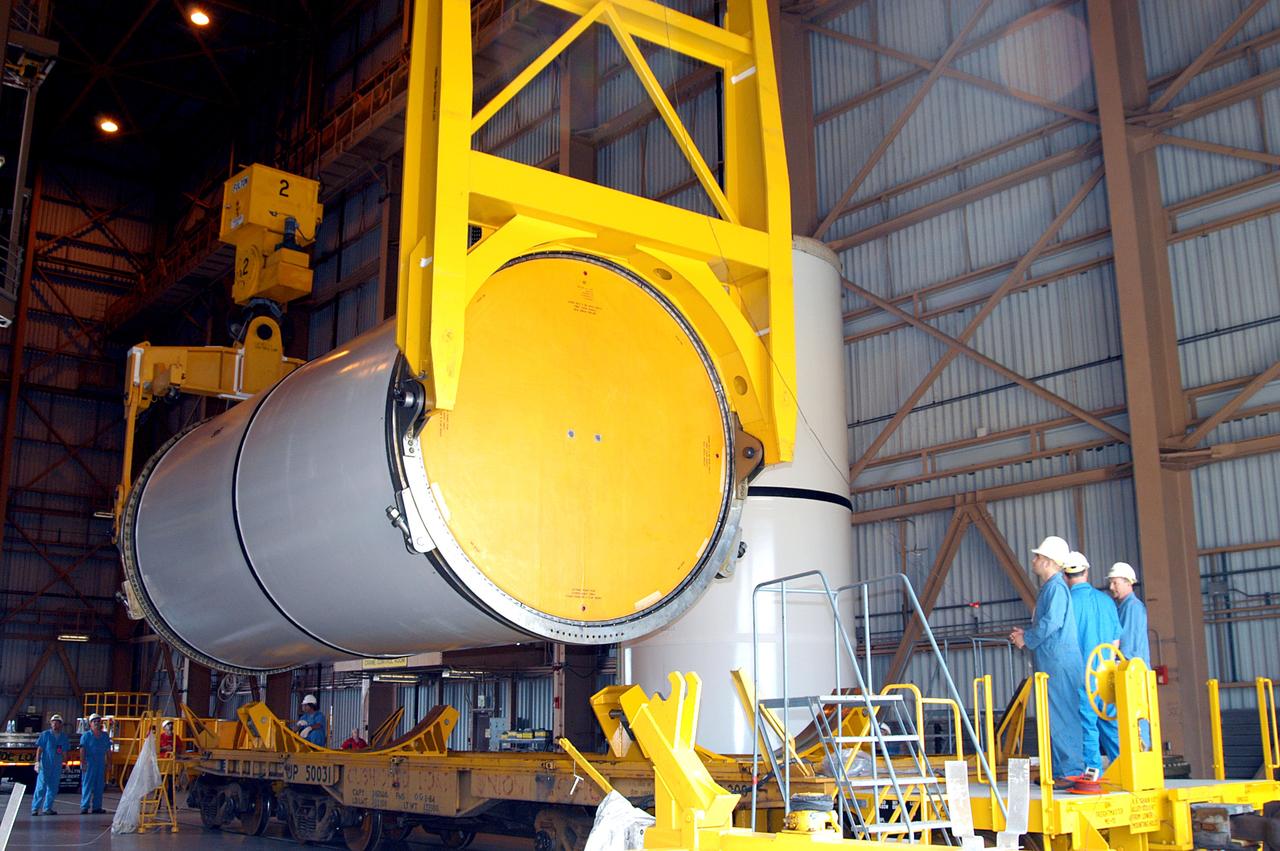 KENNEDY SPACE CENTER, FLA. -  In the Rotation Processing and Surge Facility, an SRB solid segment is lowered onto a rail car for shipment to Utah where it will be tested.  The segment was part of the STS-114 stack.  It is the first time actual flight segments that had been stacked for flight in the VAB are being returned to Utah for testing.  It will undergo firing, which will enable inspectors to check the viability of the solid and verify the life expectancy for stacked segments.
