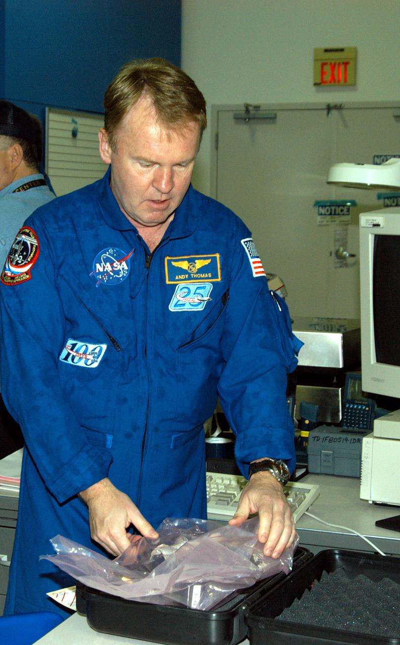 KENNEDY SPACE CENTER, FLA. -  STS-114 Mission Specialist Andrew Thomas works on equipment in the Space Station Processing Facility.  He and other crew members are at KSC for equipment familiarization.  STS-114 is classified as Logistics Flight 1 to the International Space Station,  delivering new supplies and replacing one of the orbital outpost’s Control Moment Gyroscopes (CMGs). STS-114 will also carry a Raffaello Multi-Purpose Logistics Module and the External Stowage Platform-2.  The crew is slated to conduct at least three spacewalks: They will demonstrate repair techniques of the Shuttle’s Thermal Protection System,  replace the failed CMG with one delivered by the Shuttle, and  install the External Stowage Platform.